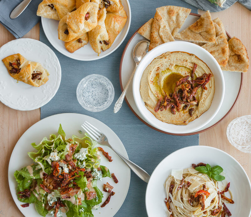 Table setting featuring fruitons® Seasoned Sun Dried Tomatoes as toppings for salads, hummus, and baked breads.