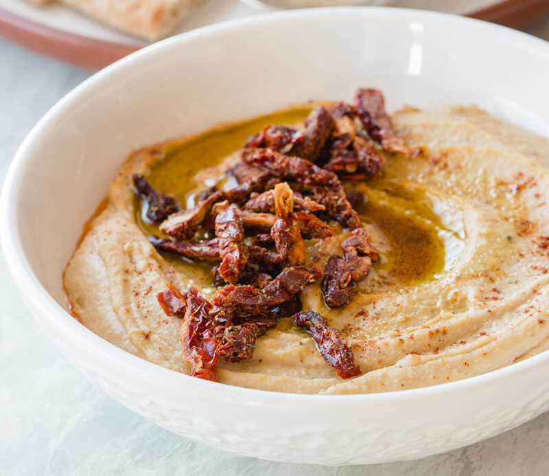 fruitons® Seasoned Sun Dried Tomatoes used as a topping on hummus with a drizzle of olive oil.