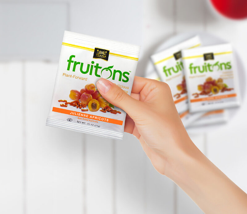 A woman’s hand holding a bag of Fruitons® Sun Dried Apricot Snacks, showcasing the convenient size—perfect for keeping a wholesome snack on hand.