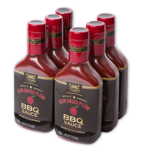 Case of six 17 oz bottles of Sun Dried Plum BBQ Sauce with black labels, made with sun dried plums, herbs, and spices. Ideal for basting or dipping, with a thick, tangy-savory flavor and dark reddish color.