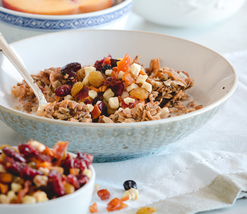 fruitons® All American Dried Fruit Blend as a topping on cereal or oatmeal, shown in a breakfast setting with a closeup of a cereal bowl.